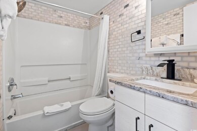 Full bathroom with decorative backsplash, brick wa