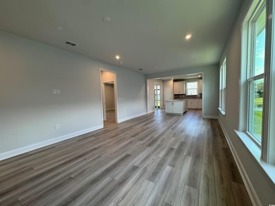 Unfurnished living room with wood finished floors, baseboards, and recessed lighting
