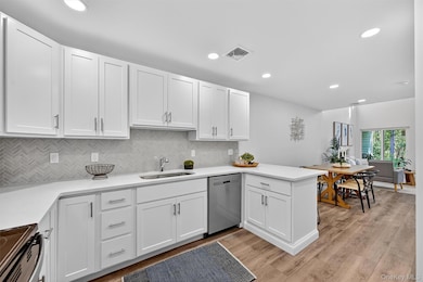 Kitchen with white cabinets, backsplash, dishwasher, black range with electric stovetop, and recessed lighting