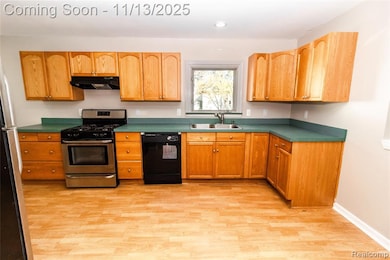 Kitchen featuring appliances with stainless steel finishes, light wood-type flooring, ventilation hood, dark countertops, and recessed lighting