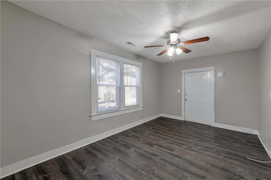 Unfurnished room featuring dark hardwood / wood-style flooring, ceiling fan, and a textured ceiling