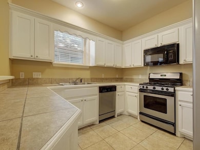 Kitchen with stainless steel appliances, white cabinetry, and light tile patterned floors