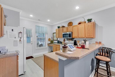 Kitchen with light wood-type flooring, crown moldi