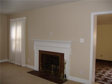 Living Room. Original fireplace and HW under carpe