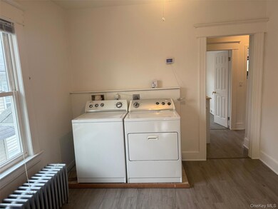 Laundry room featuring radiator heating unit, light wood finished floors, healthy amount of natural light, and separate washer and dryer