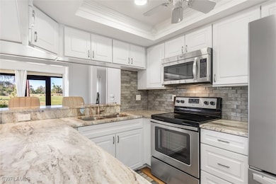 Kitchen with white cabinets, light stone counters,