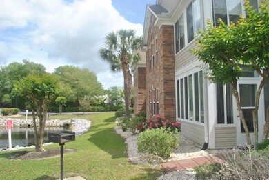 View of side of home featuring brick siding, a water view, and a yard