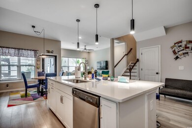 Kitchen with stainless steel dishwasher, a sink, light wood finished floors, white cabinets, and open floor plan