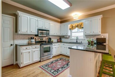 Updated kitchen with painted cabinets, subway tile, granite, counter seating, stainless appliances and a view out the backyard.