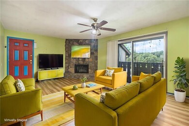 Living area with wood finished floors, a stone fireplace, and ceiling fan