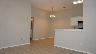 Empty room with a chandelier and light tile patterned flooring