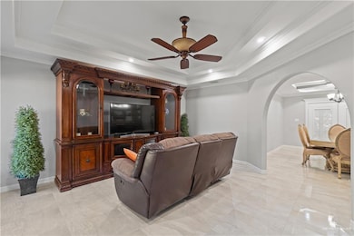 Cinema room with arched walkways, a raised ceiling, ornamental molding, a ceiling fan, and recessed lighting