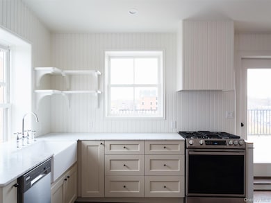 Kitchen with open shelves, stainless steel appliances, plenty of natural light, light stone countertops, and wooden walls