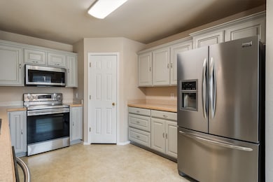 Kitchen featuring stainless steel appliances, white cabinets, and light tile floors