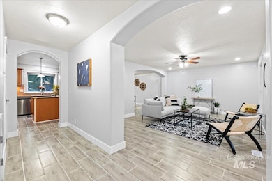 Living area featuring ceiling fan, a textured ceiling, wood finish floors, arched walkways, and recessed lighting