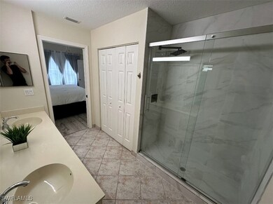 Full bath with a sink, a marble finish shower, visible vents, and a textured ceiling