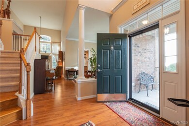 Foyer featuring decorative columns, light hardwood