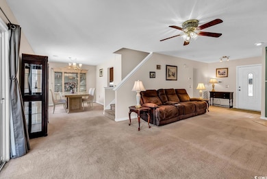 Living room with light carpet, a chandelier, stair