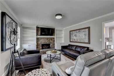 Living room featuring ornamental molding, baseboards, built in shelves, a fireplace, and wood finished floors