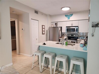 Kitchen featuring white cabinetry, sink, stainless steel appliances, and a kitchen breakfast bar