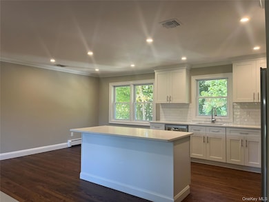 Kitchen with recessed lighting, crown molding, white cabinetry, backsplash, and dark wood-type flooring