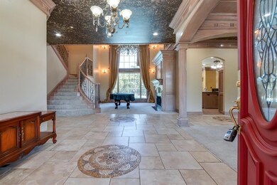 Tiled entryway featuring a notable chandelier and 