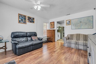 Living room with a textured ceiling, hardwood / wood-style flooring, and ceiling fan