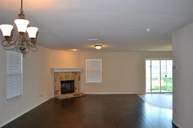 Unfurnished living room featuring an inviting chandelier, hardwood / wood-style floors, and a stone fireplace