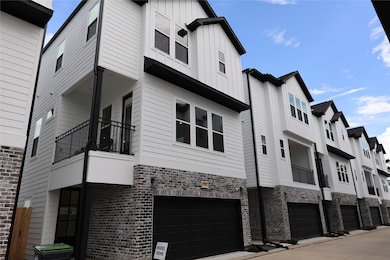 Modern three-story townhouses with a sleek design, featuring white siding, brick accents, and black garage doors. The complex has a clean, organized layout. Ideal for contemporary urban living.