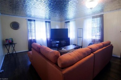 Den with vintage style ceiling and original hardwood floors