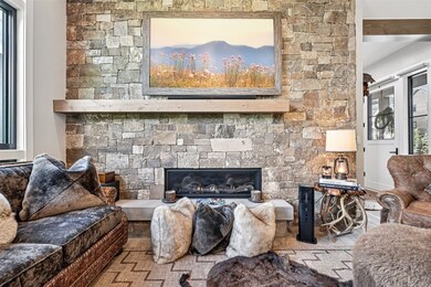 Living room with a stone fireplace and Custom Flatscreen TV, wood finished floors
