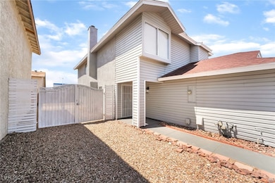 Back of house with a gate, a chimney, and stucco s