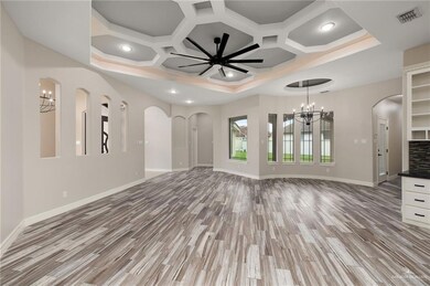 Unfurnished living room featuring coffered ceiling, light hardwood / wood-style flooring, and ceiling fan with notable chandelier