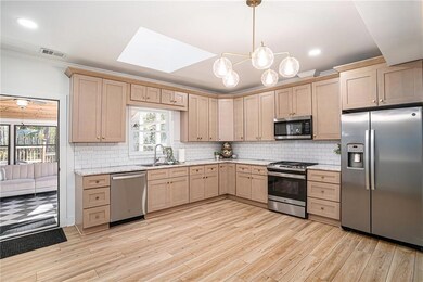 Kitchen featuring stainless steel appliances, a skylight, tasteful backsplash, hanging light fixtures, and recessed lighting