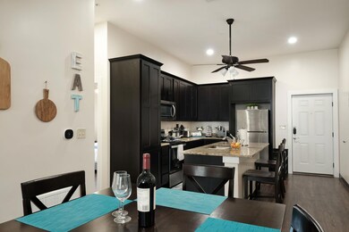 Kitchen with dark cabinets, stainless steel appliances, light stone countertops, a kitchen breakfast bar, and ceiling fan