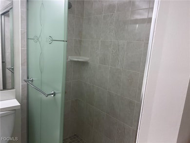 Bathroom with toilet, a shower with door, and vanity