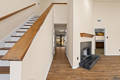 Interior space with visible vents, baseboards, a fireplace, wood finished floors, and a towering ceiling
