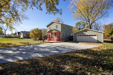 View of front of property with an outbuilding, a garage, and a front lawn