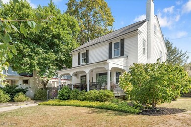 View of front of home with covered porch, a chimney, roof with shingles, and a front yard