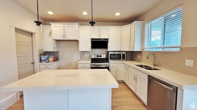 Kitchen featuring appliances with stainless steel finishes, backsplash, light wood finished floors, white cabinetry, and recessed lighting