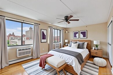 Bedroom featuring a baseboard radiator, light wood-style floors, a ceiling fan, a wall mounted air conditioner, and a view of city