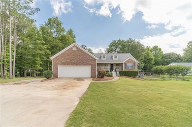 View of front facade featuring a front yard, a garage, concrete driveway, brick siding, and covered porch