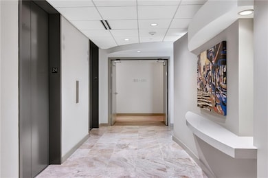 Hallway with elevator, a paneled ceiling, and recessed lighting