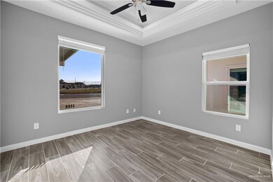 Empty room with a ceiling fan, a tray ceiling, baseboards, and wood tiled floor