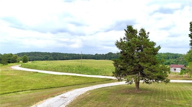 Surrounding community featuring a view of trees, gravel driveway, and a lawn