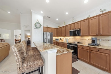 Kitchen with ornamental molding, brown cabinets, stainless steel appliances, backsplash, and arched walkways