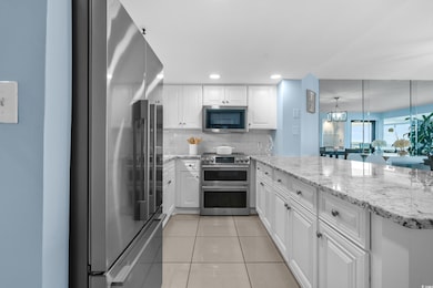 Kitchen featuring appliances with stainless steel finishes, a peninsula, white cabinets, decorative backsplash, and light tile patterned floors
