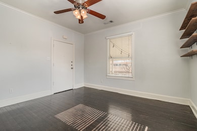 Spare room featuring crown molding, dark wood-style floors, and ceiling fan