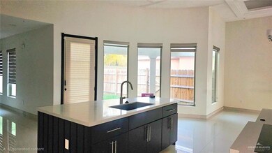 Kitchen with dark cabinetry, a kitchen island with sink, and light stone countertops
