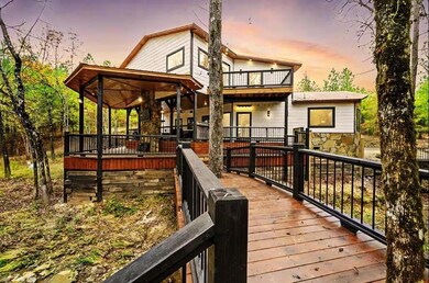 Chalet / cabin featuring stone siding, covered porch, a metal roof, and driveway